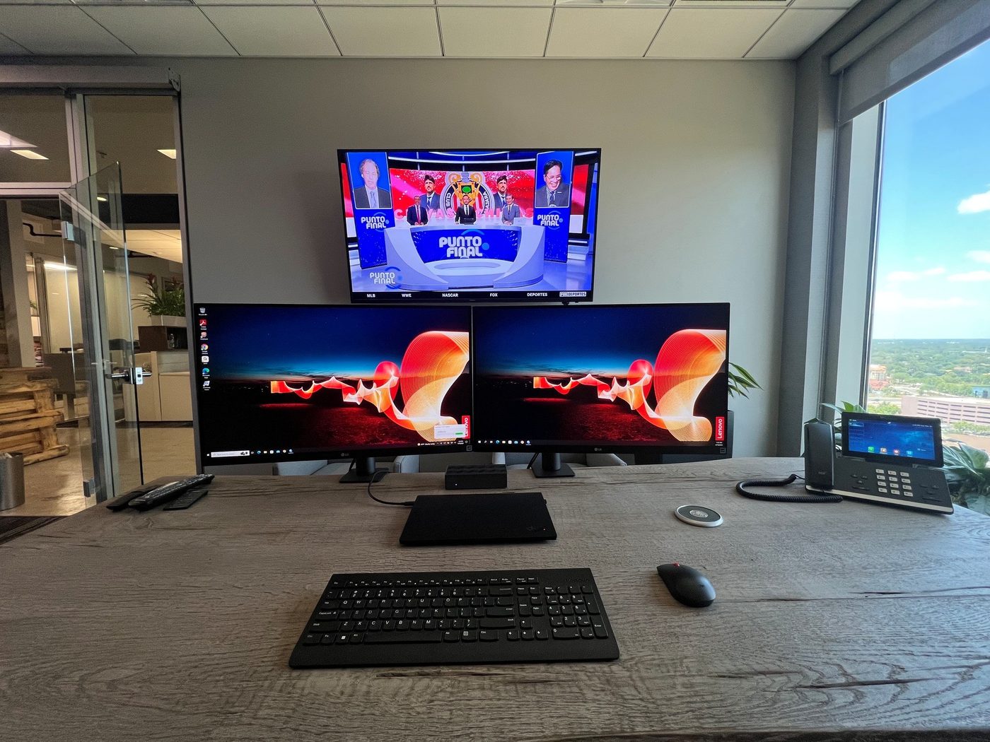 Executive office technology installation with dual monitors and wall-mounted display for a property management client